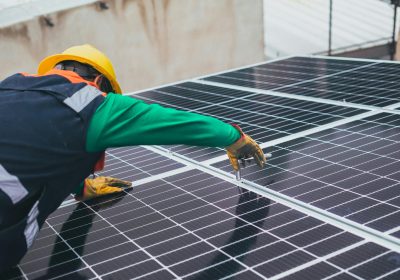Technician installing solar panels on a rooftop for sustainable energy solutions.